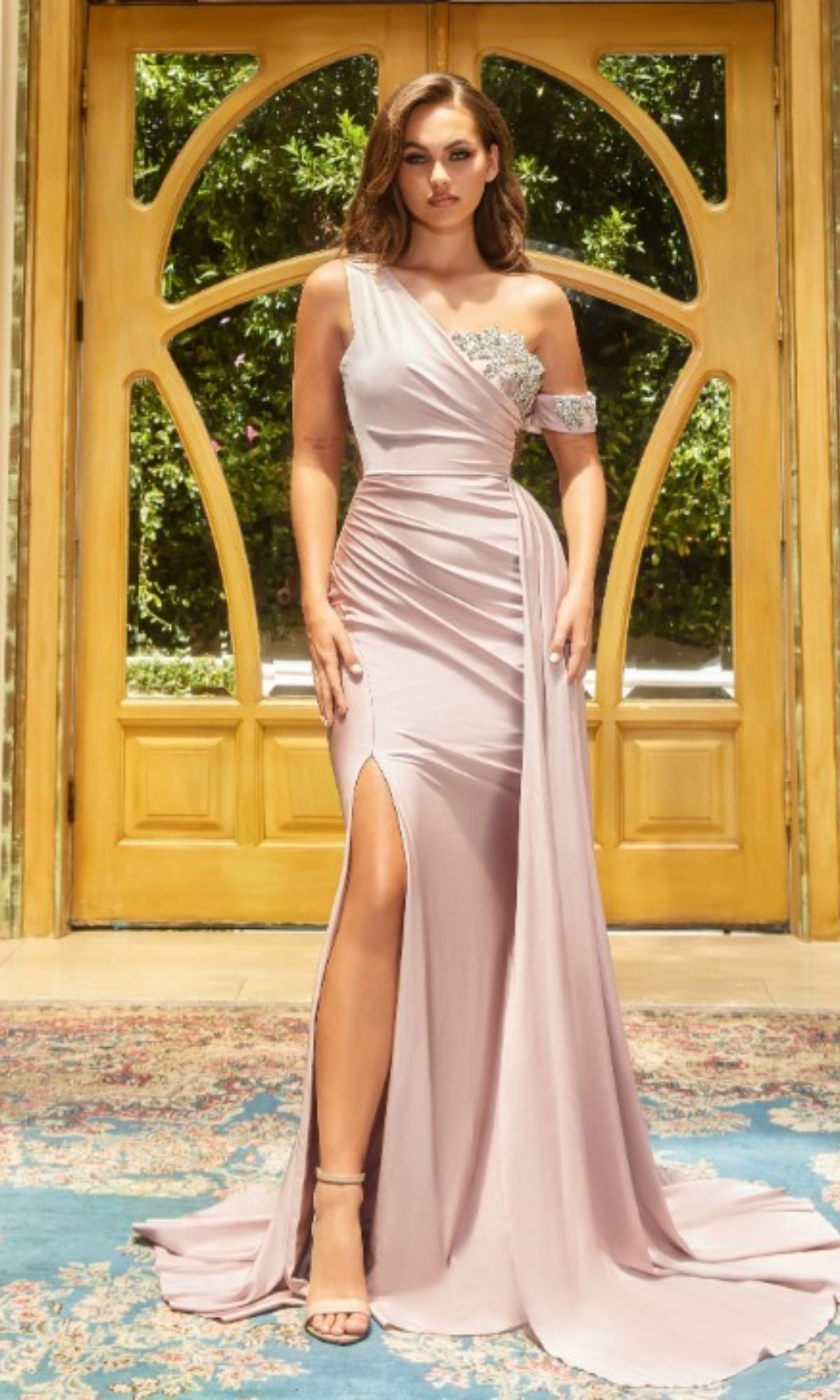 Woman in a mauve, one-shoulder Long Formal Dress PS22222 by Portia and Scarlett featuring a thigh-high slit and embellished sweetheart neckline, standing indoors before wooden double doors with glass panels.
